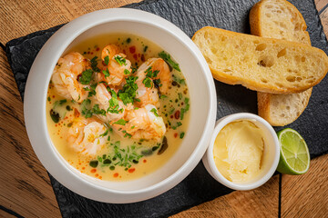 Fresh shrimp swimming in a flavorful broth, paired with golden bread and creamy butter