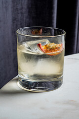 A refreshing drink with a citrus slice rests on a marble table in soft evening light