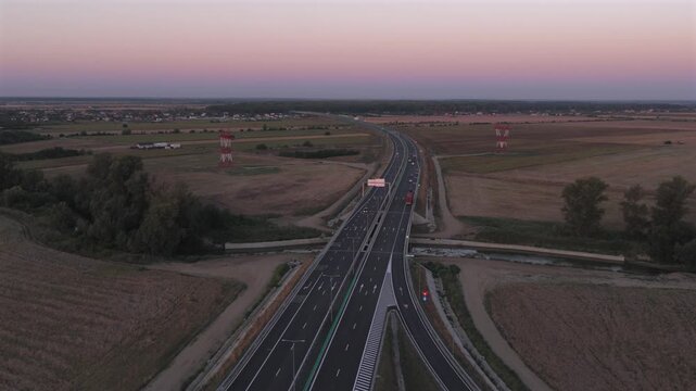 Bucharest A0 highway 4k video. Aerial view of a curved section of the A0 highway near Bucharest during the warm light of sunrise, highlighting the road lines and safety barriers. Roads of Romania.