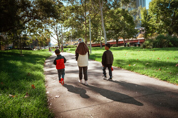 A family strolls through a sunlit park, enjoying nature and togetherness.