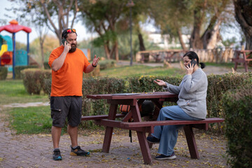 Modern freelancers working on laptops in nature. Man and woman working on laptops in public park. Remote work concept with couple using computers outdoors.
