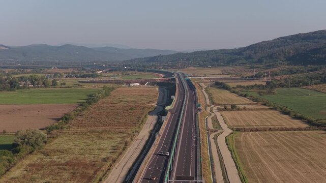 A1 highway from Bucharest to Pitesit Curtea de Arges and Sibiu 4K video. Newly built A1 Highway in Romania, cutting through rural fields and valleys, with mountains visible in the distance.