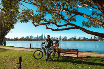 A man is riding a bike close to a beautiful scenic waterfront and city skyline