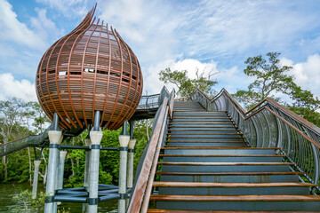 View of wooden stairs leading to a pod-shaped structure against a backdrop of lush greenery and a partly cloudy sky, Sungei Buloh Wetland Reserve, Neo Tiew Crescent, Singapore.