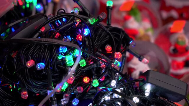 Blinking LED Christmas lights tangled on wires creating colorful festive decoration close up in winter indoors interior