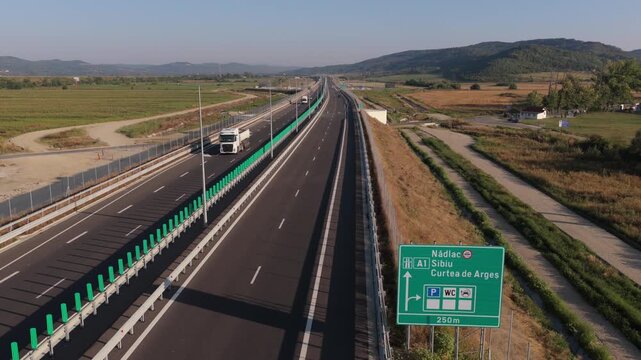 A1 highway from Bucharest to Pitesit Curtea de Arges and Sibiu 4K video. Newly built A1 Highway in Romania, cutting through rural fields and valleys, with mountains visible in the distance.