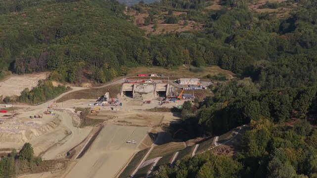Highway construction in Romania 4k video. Aerial view of the A1 Motorway construction site near Curtea de Arges, showing an unfinished bridge over a valley and forested hills. Bucharest Sibiu road