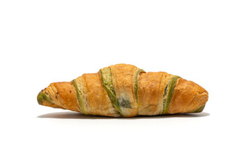 A pistachio-filled croissant is shown from a low side angle on a white surface. The layered dough and creamy green filling are clearly visible.