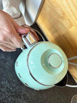 Woman holding SMEG electric kettle in kitchen interior, everyday domestic life, Ukraine, Yaremche, November 19, 2025