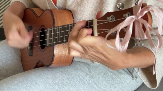 Close up Ukulele or uke string instrument video popular on Hawaii islands. Woman playing nylon strings during music lessons in living room. Musical education and art people concept 4K footage