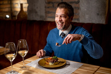 Man enjoys dinner at restaurant with wine and food in evening setting