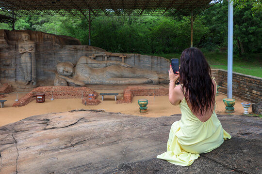 Woman photographing the majestic Reclining Buddha at Gal Vihara, Sri Lanka.