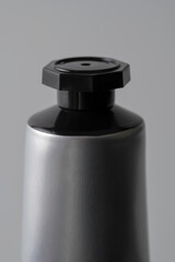 A silver metal tube stands alone on a gray background. This clean, focused product shot is perfect for modern skincare, cosmetics, or pharmaceutical advertising.