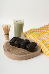 Chocolate sponge cake on a wooden tray with matcha drink, traditional food from Bandung, Indonesia