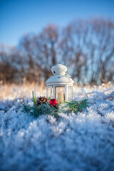 Holiday background with spruce wreath and Christmas candlestick standing in New Year's park with shiny crystals of hoarfrost on a frosty morning