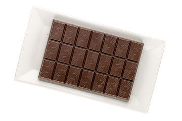 One bar of dark chocolate with a ceramic plate isolated on a white background, macro. Top view.