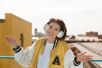 smiling middle aged woman with headphoneson  enjoying the view of the city from a high vantage point. Audio guide. Mindfulness and feel-good moments. Audio healing. 