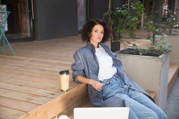  remote workers. Working from Anywhere.  middle aged woman    is working on a laptopon a bench on the street in a cafe. startup