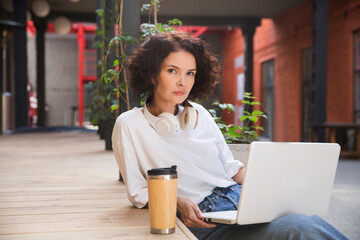 remote workers. Working from Anywhere.  middle aged woman    is working on a laptopon a bench on the street in a cafe. startup