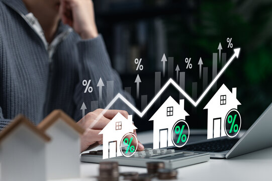 Real estate interest rate and housing market growth concept. Businesswoman calculates mortgage and property investment with rising graph, home icons, and percent signs showing financial increase. - Powered by Adobe