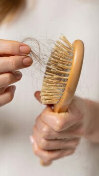 Hair loss strands caught in wooden hairbrush, close view of shedding during grooming routine, damaged hair fibers and breakage, personal care concern, scalp health and hair fall problem concept