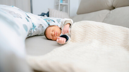 Peaceful sleeping newborn under cozy blanket at home