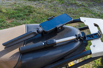 Smartphone tripod and selfie stick placed on motorcycle seat outdoors