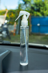 Transparent spray bottle with trigger nozzle placed on car dashboard outdoors