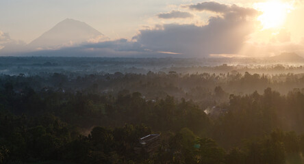Misty sunrise over Bali's lush landscape with volcano