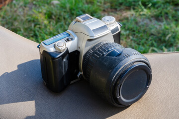 DSLR camera with zoom lens resting on cushion with grass background