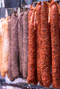 Assorted sausages on display at the market with various coatings.