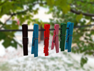 "A line of colorful clothespins holding the secrets of laundry day, suspended between the green canopy and the snowy ground. A small pop of domestic life against nature's backdro