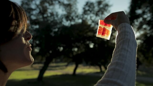 Mujer embarazada comiendo jam&oacute;n ib&eacute;rico al atardecer con la loncha expuesta al sol