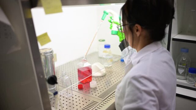 Female scientist pipetting liquid in a laminar flow hood