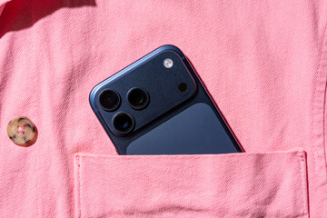 Smartphone in a pink shirt pocket with a button