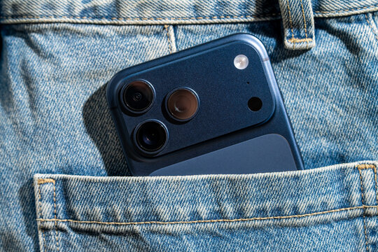 Smartphone peeking from denim pocket with triple camera