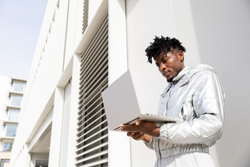 Futuristic professional using a laptop outside modern building