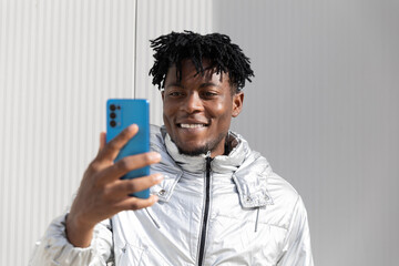 Man smiling with modern smartphone in silver jacket