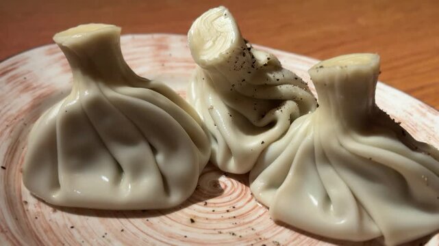 Close-up of traditional khinkali in natural warm lighting, Inviting rustic ceramic plate showcasing freshly steamed Georgian khinkali in warm natural illumination.