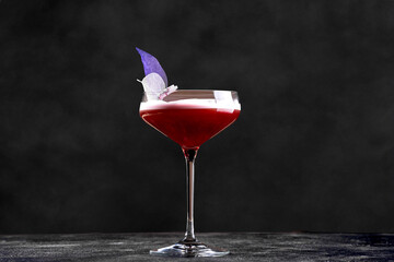 The drink features two layers: a deep red liquid base and a smooth, light pink (or white) foam on top, suggesting a sour, fizz, or flip-style cocktail