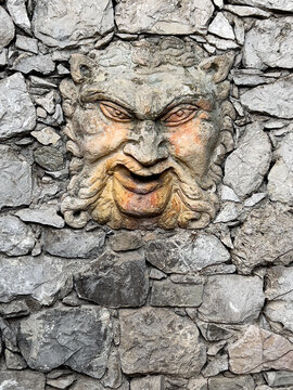 Grotesque stone mascaron carving adorning ancient rock wall