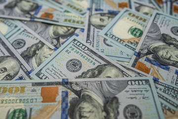 Background of scattered US 100 dollar banknotes, a symbol of prosperity.