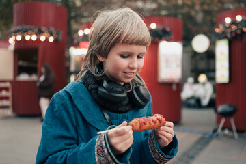 Happy teenage girl holding Corn dog at festival street fair