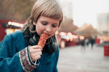 Happy teenage girl holding Corn dog at festival street fair