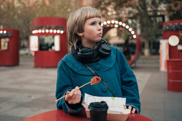 Teenage girl eating corn dog at festival street fair in city
