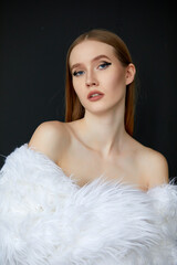 Portrait of a woman, taken in close-up. She is wearing a long white fur coat, and her hair is a chestnut shade.