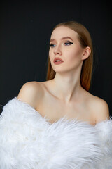 Portrait of a woman, taken in close-up. She is wearing a long white fur coat, and her hair is a chestnut shade.
