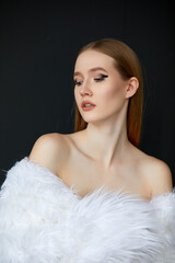 Portrait of a woman, taken in close-up. She is wearing a long white fur coat, and her hair is a chestnut shade.