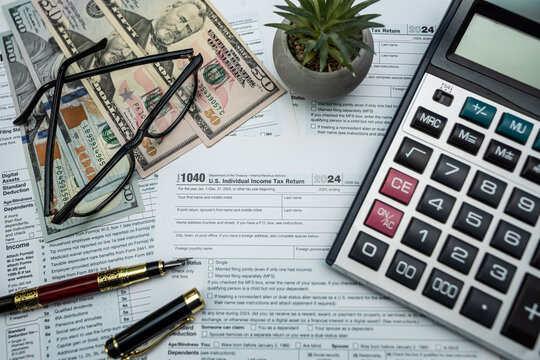 US dollar bills and form 1040 with glasses and calculator ready for 2026 tax processing - Powered by Adobe