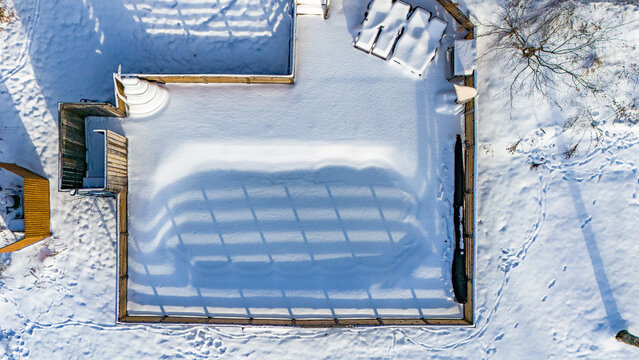 Aerial view of frozen above ground swimming pool covered in snow during winter